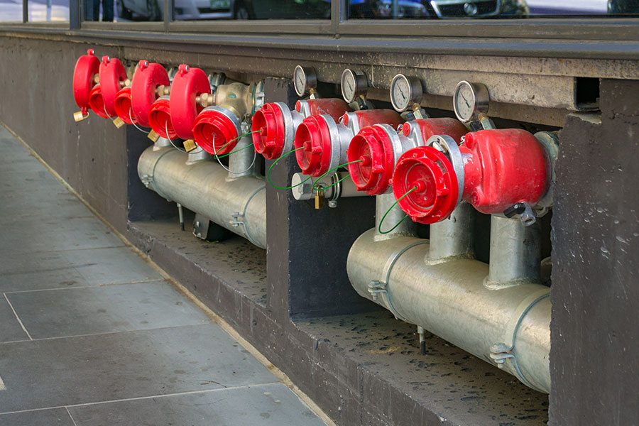 Bright hydrant boosters in a row with metal pipes and red caps.